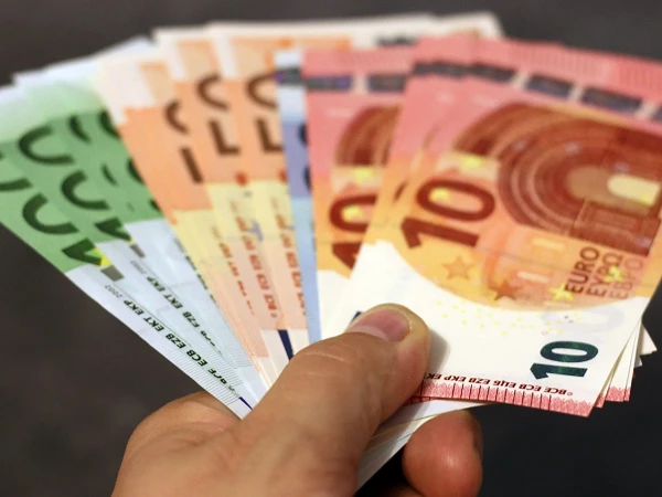Eine Hand hält verschiedene Euro-Scheine in unterschiedlichen Farben und Nennwerten, darunter 10 Euro und größere Beträge.