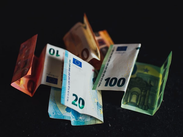 Verschiedene Euro-Scheine in unterschiedlichen Größen und Farben liegen übereinander auf einem dunklen Hintergrund.