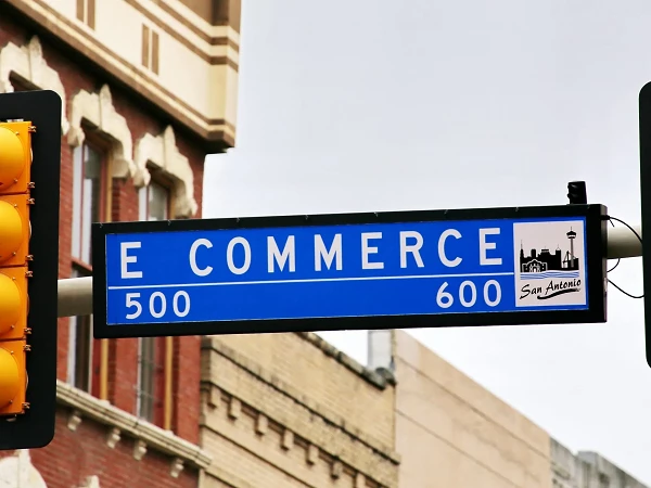Das Verkehrsschild zeigt die Beschilderung für die East Commerce Street in San Antonio, mit den Hausnummern 500 und 600, unter einem grünen Lichtsignal.