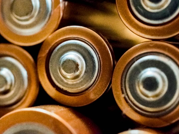 Eine nahaufgenommene Ansicht von mehreren Batterien, die auf ihren oberen Enden angeordnet sind, wobei die Metallkontakte und die runden, orangenen Umhüllungen sichtbar sind.