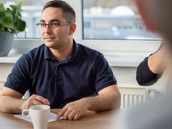 Mitarbeiter im Gespräch am Besprechungstisch mit Notizen und Kaffeetasse