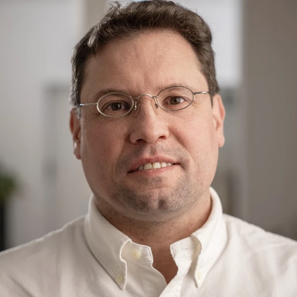 lächelnder Mann mit braunem Haar, Brille und Hemd